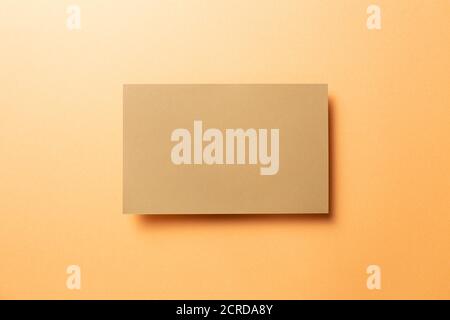 Kraft brown memo pad, empty paper on orange background. top view, copy space Stock Photo
