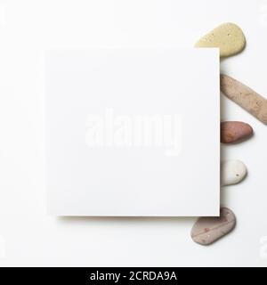 White memo pad, empty paper with pebble stones on white background. flat lay, top view, copy space Stock Photo