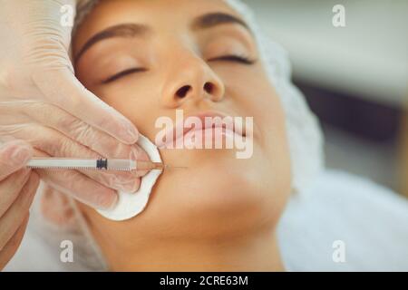 Woman recieving facial beauty botox injection to chin from professional cosmetologist Stock Photo