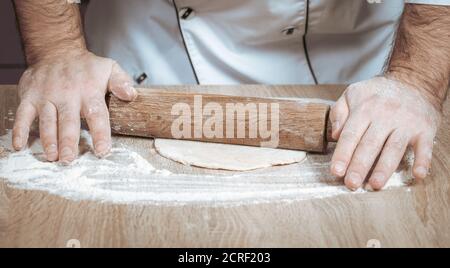 male cook kneads dough on the table, hands close-up Stock Photo