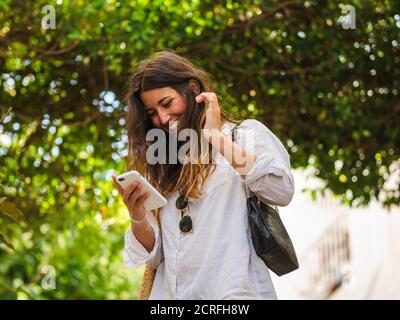 Young Caucasian woman looking at a phone and smiling Stock Photo