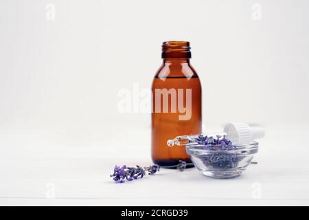 Mockup image of dropper bottle with lavender essential oil and lavender flowers on white background with copyspace for text. Trendy toned photo for Stock Photo