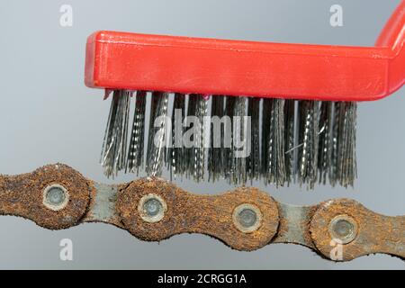 The steel brush cleans a rusty chain, close up view. A bicycle chain maintenance, macro view. Stock Photo