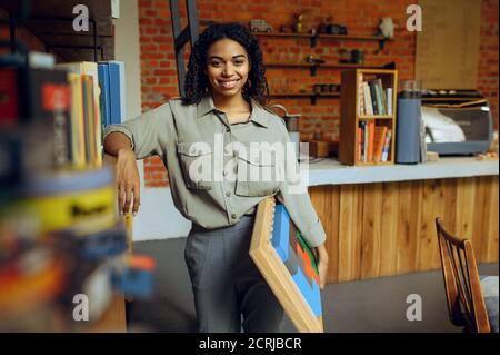 Female student poses at the shelf in library Stock Photo