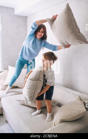 Mother and little son having pillow fight on sofa at home Stock Photo