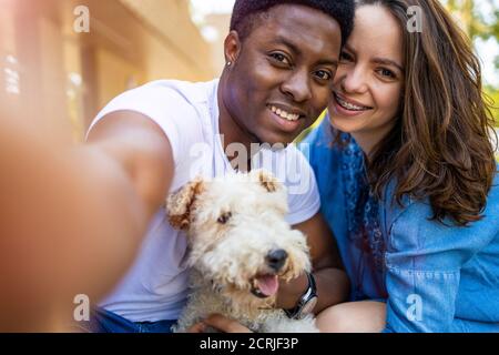 Happy young couple with their pet dog outdoors Stock Photo