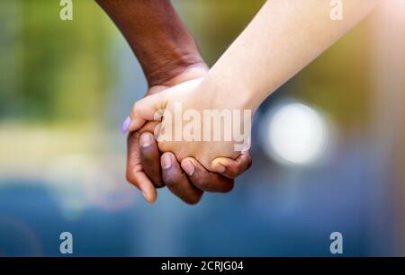 Interracial couple holding hands outdoors Stock Photo