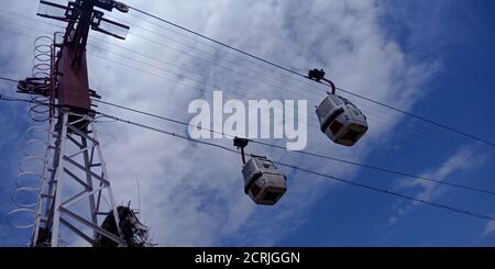 Two Ropeway Trolly car hanging on river side hill station in blue sky background. Stock Photo