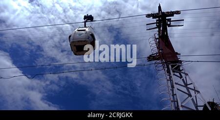 Single Ropeway Trolly car hanging on river side hill station in blue sky background. Stock Photo