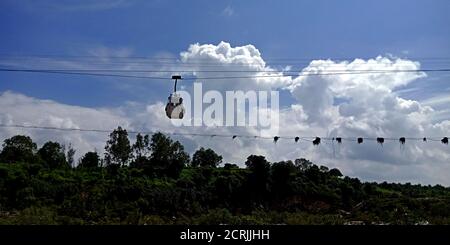 Ropeway Trolly car hanging on river side hill station in blue sky background. Stock Photo