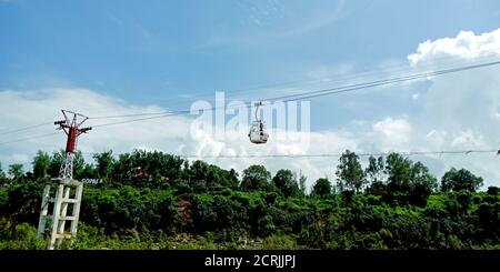 Ropeway Trolly car hanging on river side hill station in blue sky background. Stock Photo