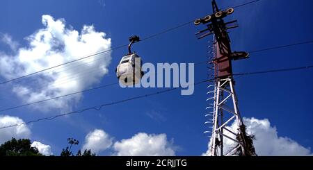 Single Ropeway Trolly car hanging on river side hill station in blue sky background. Stock Photo