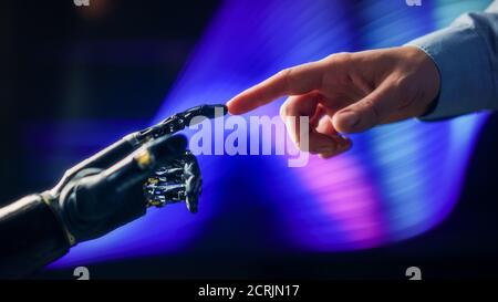 Humanoid Robot Arm Touches Human Hand Connecting Fingers. Humanity and Artificial Intelligence Unifying Gesture.Technology Merges with Creative Human Stock Photo