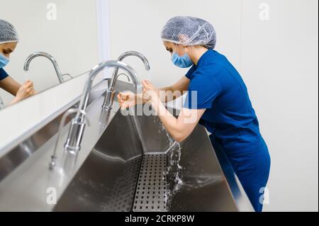 Female surgeon washes hands, preparing for surgery Stock Photo