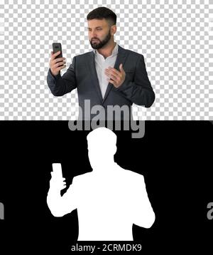 Businessman making a video call with his smartphone, Alpha Chann Stock Photo