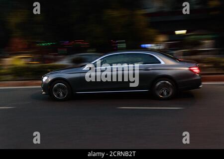 Panning technique of grey car which is going to market at night on the road Stock Photo