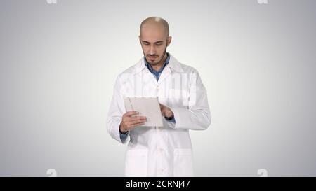Mature male doctor holding digital tablet using it and walking o Stock Photo