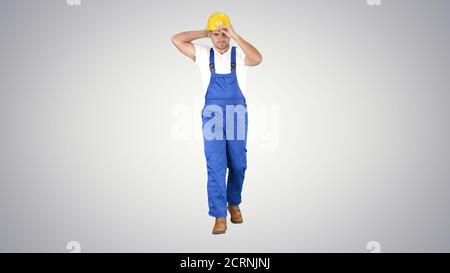 Construction worker walking and putting on hard hat or helmet on Stock Photo