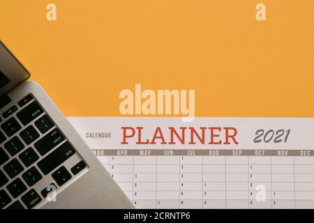 Computer laptop and calendar planner on top of yellow tabletop. Copy space. Stock Photo