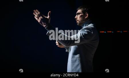 Tech Conference Stage: Speaker Talks about Product. Neural Networks, Artificial Intelligence, Big Data and Machine Learning. Screen Shows Infographics Stock Photo