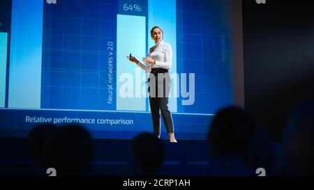 On Stage, Successful Female Speaker Presents Technological Product, Uses Remote Control for Presentation, Showing Infographics, Statistics Animation Stock Photo
