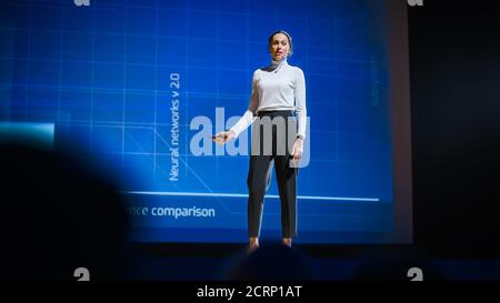 On-Stage Successful Female Speaker Presents Technological Product, Uses Remote Control for Presentation, Showing Infographics, Statistics Animation on Stock Photo