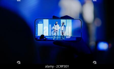 Audience Use Smartphones to Record Two Speakers Talking on Business Conference. Public Uses Mobile Phones to Shoot Video of Two Star Presenters on Stock Photo