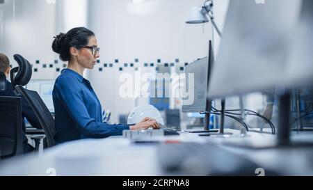 Low Angle Shot of a Female Engineer Working on Personal Computer. She Works with Team of Industrial Professionals in Office that's Located in the Stock Photo