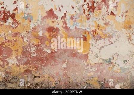 Detail of old flaky chipped cracked wall with scrapes and layers of paint peeling off as an aging process of neglected house ruin facade Stock Photo