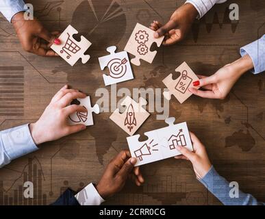 Creative Collage With Business People Holding Puzzle Pieces With Marketing Strategy Icons Stock Photo