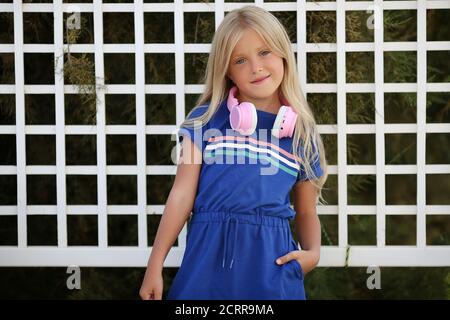 pretty preteen girl having fun outdoors with headphones in summer warm day. Stock Photo