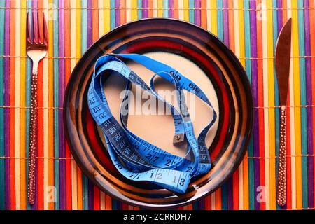 Clean plate with measurement tape and cutlery on table cloth Stock Photo