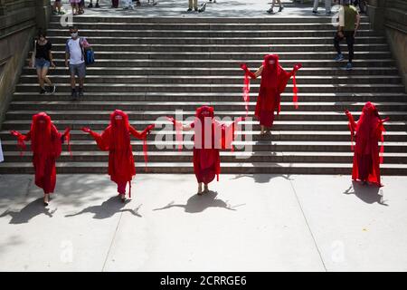 The Red Rebels, Brigade, who are a branch of Extinction Rebellion, dressed in bright red to signify the blood of species that have died as a result of climate change, as well as those that will die in the future demonstrate and march at Bethesda Fountain in Central Park organized by 'Extinction Rebellion' to bring attention to the immediate need for system change in the US and around the world to combat  the climate crisis that is now being experienced world wide in the form of wildfires, hurricanes, droughts and floods along with air and water pollution at an unprecedented scale. Stock Photo