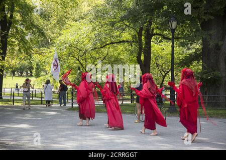 The Red Rebels, Brigade, who are a branch of Extinction Rebellion, dressed in bright red to signify the blood of species that have died as a result of climate change, as well as those that will die in the future demonstrate and march at Bethesda Fountain in Central Park organized by 'Extinction Rebellion' to bring attention to the immediate need for system change in the US and around the world to combat  the climate crisis that is now being experienced world wide in the form of wildfires, hurricanes, droughts and floods along with air and water pollution at an unprecedented scale. Stock Photo