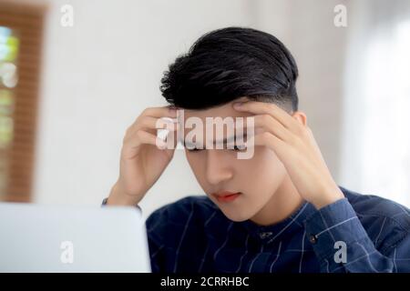 Young asian business man headache during working on laptop computer with deadline on desk at home, businessman with failure exhausted and tired, stres Stock Photo