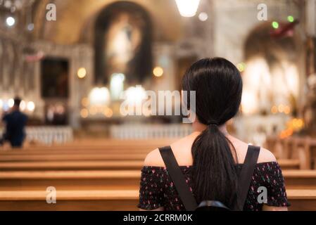 A chinese woman sitting in a pew within the historial chapelle notre dame de bon secours in old montreal quebec canada. Stock Photo