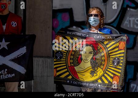 A protester wearing a facemask is seen displaying a flag in favor of the Catalan republic during the protests.Concentration of the Catalan Independence movement infront of the Department of Economy to celebrate the third anniversary of the 20s protests that were the origin of the judicial processes against the Catalan leaders and the independence process in Catalonia. Stock Photo