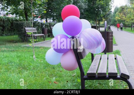Multicolored balloons on a wooden bench in a city park. Stock Photo
