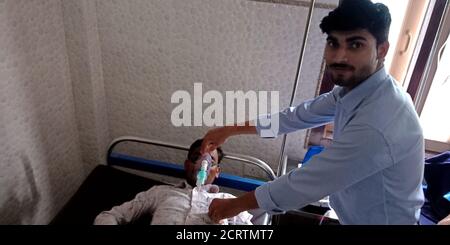 DISTRICT KATNI, INDIA - SEPTEMBER 28, 2019: An indian male nurse putting oxygen mask on patient mouth in ward room at city public hospital. Stock Photo