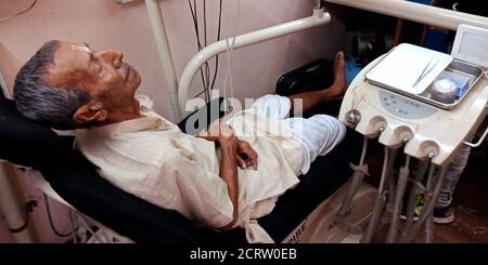 DISTRICT KATNI, INDIA - SEPTEMBER 29, 2019: An indian village elderly patient lying on dentist chair for oral infection testing at dental clinic in ci Stock Photo