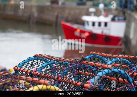 Stack of lobster pots with trawler in the background, Dunbar Harbour Stock Photo