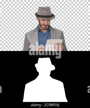 Handsome smiling arab man in a hat walking and using tablet, Alp Stock Photo