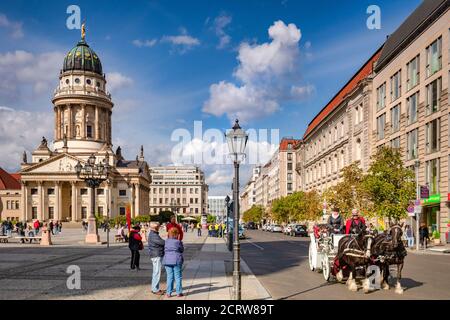 22 September 2018: Berlin, Germany - Horse-drawn carriage ride in Gendarmenmarkt Square, with the French Church on the left, tourists watching as it g Stock Photo