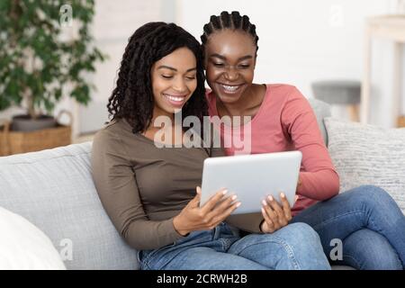 Smiling black women using digital tablet at home Stock Photo