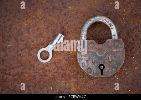 An old padlock with a key on a rusty sheet of metal, close-up, selective focus Stock Photo