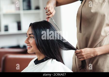 Young brunette woman getting short haircut at hairdressers, close up