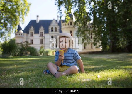 Cute child, toddler boy, eating ice cream in a park on a summer sunny day Stock Photo