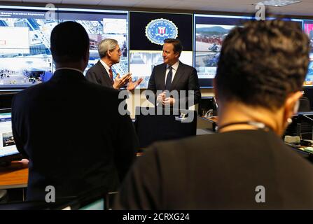 FBI operations center staff look on as FBI Director Robert Mueller (centre, L) talks with Britain's Prime Minister David Cameron (centre, R) as images from the bombings at the Boston Marathon are projected behind them, during a tour of the Strategic Information Operations Center (SOIC) at the headquarters of the Federal Bureau of Investigation in Washington, May 13, 2013. REUTERS/Jim Bourg  (UNITED STATES - Tags: POLITICS CRIME LAW)