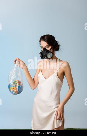 woman in gas mask holding plastic bag with globe on grey, ecology concept Stock Photo