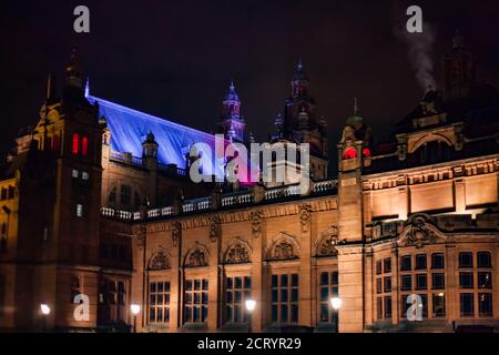 Glasgow, Scotland in fall. Kelvingrove Art Gallery and Museum at night. Color illumination of building. Black night sky.